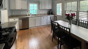 Una cucina moderna con mobili bianchi, un tavolo da pranzo con sedie, un fornello e una macchina da caffè.