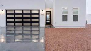 Een modern huis met twee verdiepingen, een garage, oprit en een grindpad.