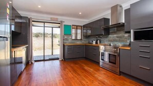 A modern kitchen with grey cabinets, a stainless steel oven, and a large window. - Saje Farm by Your Innkeeper Mudgee (Cooks Gap)