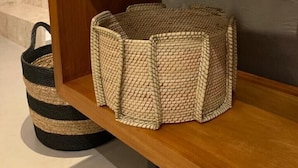 A wooden shelf with woven baskets and a potted plant.
