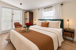Ein Hotelzimmer mit einem Bett, einem Sessel, einem Nachttisch, einer Lampe und einem Fenster mit Vorhängen.