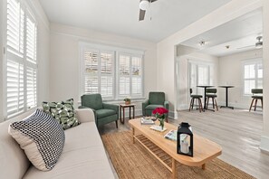 Ein Wohnzimmer mit einer Couch, zwei Sesseln, einem Couchtisch und einem Essbereich mit Tisch und Stühlen.