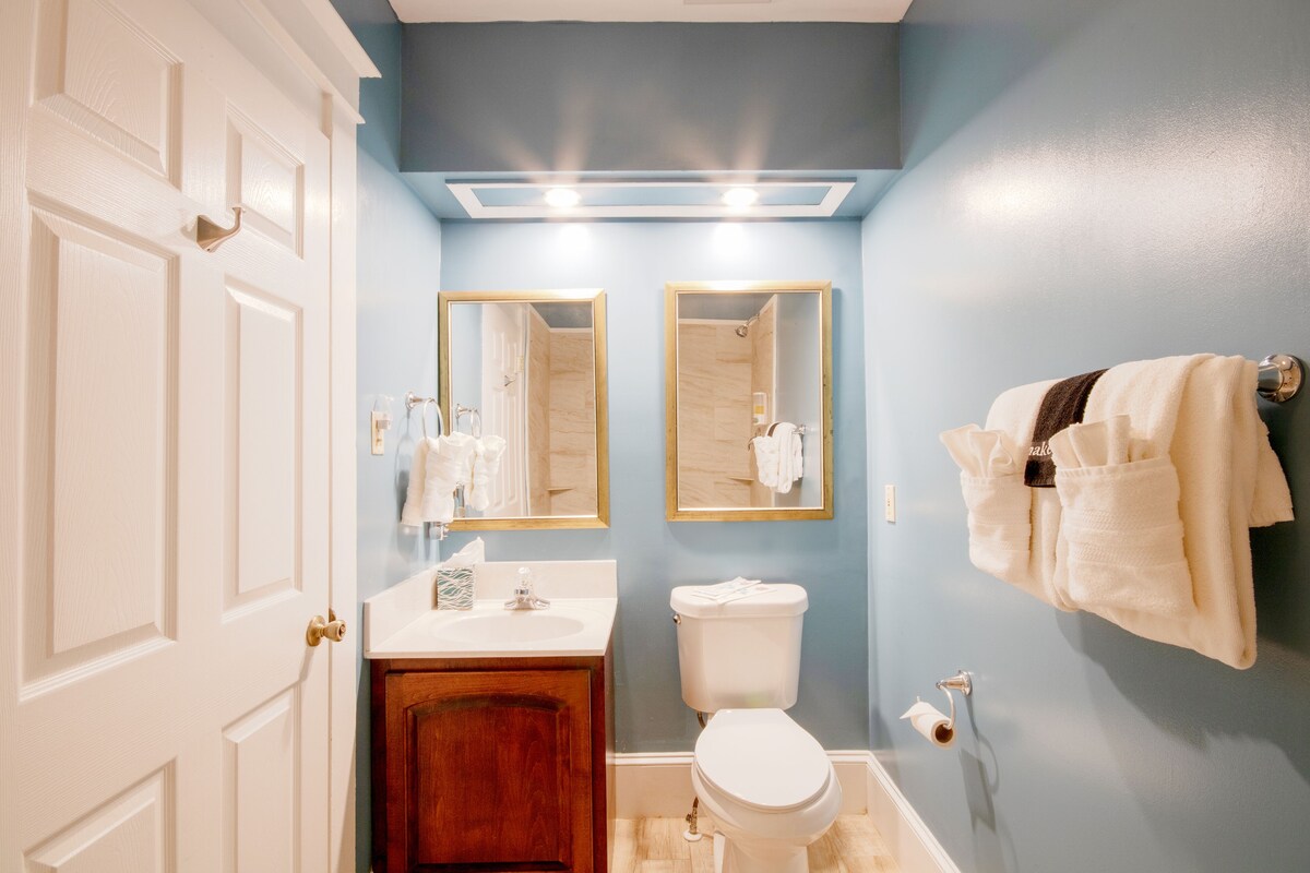 A bathroom with a white toilet, a sink with a mirror above it, and a towel rack on the wall.