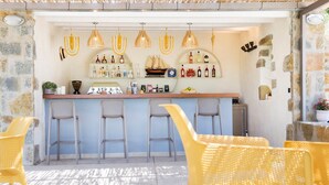 Zona de bar amb cadires de vimetes, una barra plena de botelles i una decoració marina.