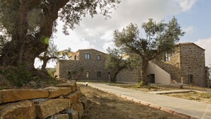 Edifici de pedra amb mur de pedra i arbres al davant.