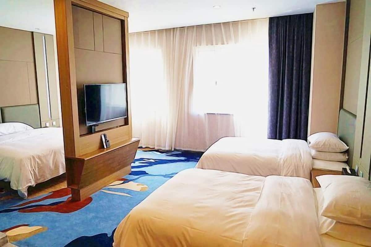 Une chambre d’hôtel avec deux lits, une télévision et une grande fenêtre avec des rideaux.