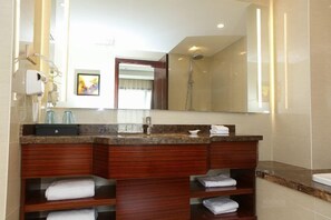 Une salle de bain moderne avec un grand miroir, une douche et un meuble-lavabo doté d’un évier et de porte-serviettes.