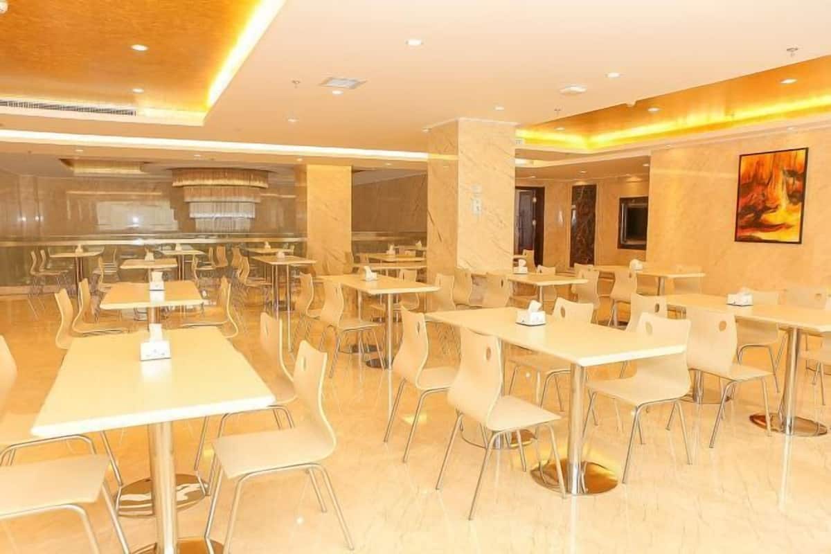 Un vaste espace dédié à la salle à manger, avec de nombreuses tables et chaises, un sol en marbre et un aménagement intérieur moderne.