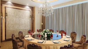 A round table with a floral centerpiece, surrounded by upholstered chairs, in a well-lit room with a chandelier. - Zhongji Garland Hotel (Tianjin)