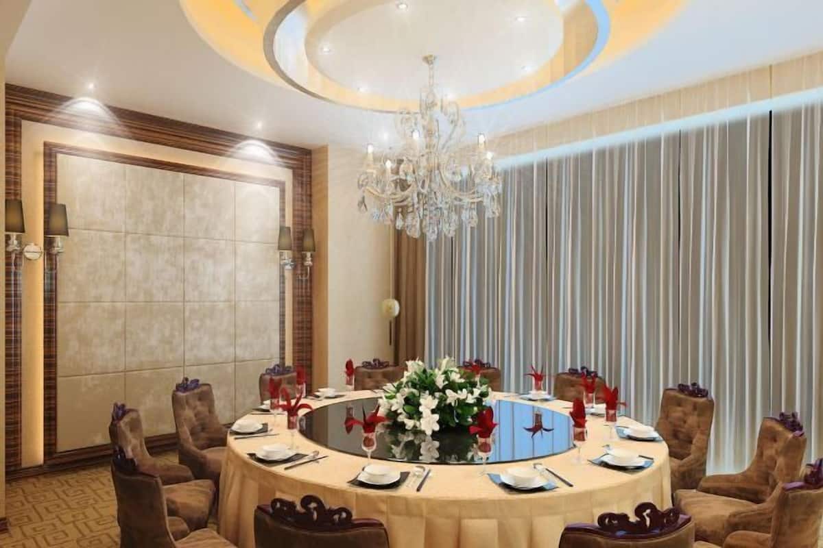 Une table ronde agrémentée d’un arrangement floral, entourée de chaises rembourrées, dans une pièce bien éclairée et ornée d’un lustre.