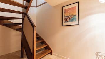 A wooden staircase with a framed poster on the wall.