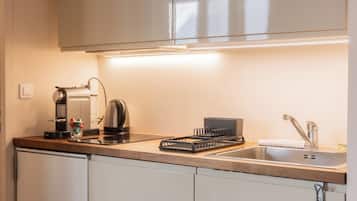 A modern kitchen with a coffee maker, kettle, and dish rack.