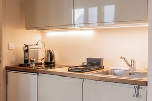 Una cocina moderna con cafetera, hervidor y escurreplatos.