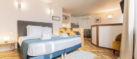 A modern hotel room with a bed, bedside table, and a small desk.