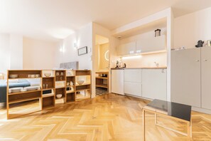 A modern kitchen with white cabinets, a black countertop, and wooden shelving units. - Magnificent Bordeaux studio in beautiful stone in the heart of the city (Bordeaux)