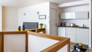 A modern apartment with a kitchenette, a bed with a grey headboard, and a small dining area. - Magnificent Bordeaux studio in beautiful stone in the heart of the city (Bordeaux)