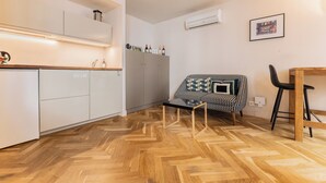 A compact kitchen with white cabinets, a wooden countertop, and a herringbone floor pattern. - Magnificent Bordeaux studio in beautiful stone in the heart of the city (Bordeaux)