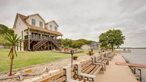 A waterfront property with a large house featuring a porch and a staircase leading to a deck. - Lake Granbury Fishing Escape w/ Dock & Kayaks! (Granbury)