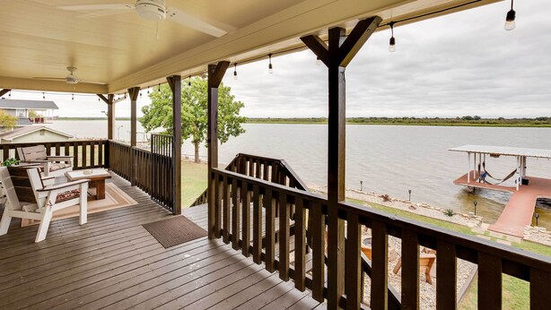 A wooden deck with outdoor furniture, a railing, and a view of a body of water. - Lake Granbury Fishing Escape w/ Dock & Kayaks! (Granbury)