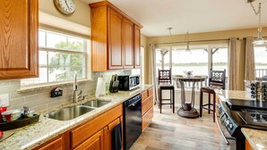 A kitchen with wooden cabinets, a dishwasher, a microwave, and a stove. There is a window with a view of the outdoors. - Lake Granbury Fishing Escape w/ Dock & Kayaks! (Granbury)
