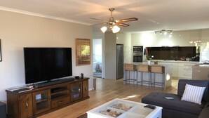Ein modernes Wohnzimmer mit Flachbildfernseher, einer Holz-Unterhaltungsecke, einem weißen Couchtisch und einem grauen Sofa.