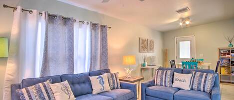 A living room with two blue sofas, a ceiling fan, a coffee table, and a lamp.