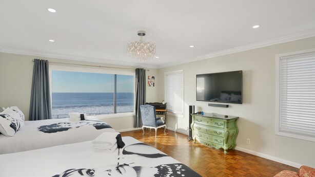 Un dormitorio con dos camas, televisión, cómoda y vista al océano.