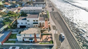 Vista aérea de una zona residencial costera con casas, una carretera y una playa.