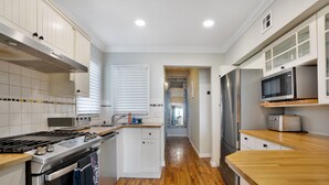 Una cocina moderna con armarios blancos, electrodomésticos de acero inoxidable y suelo de madera.