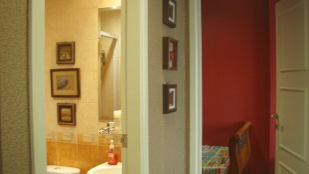 A bathroom with a toilet, sink, and mirror. There are framed pictures on the wall. - Adaru Property @city Home Apartmen KLP GDG by Zuzu (Jakarta)