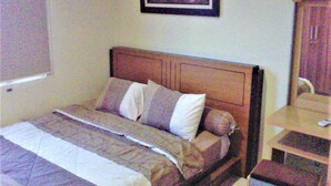 A neatly made bed with a wooden headboard, a bedside table, and a framed picture on the wall. - Adaru Property @city Home Apartmen KLP GDG by Zuzu (Jakarta)
