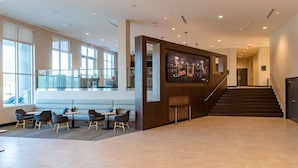 A spacious lobby with a modern design, featuring a seating area with tables and chairs, a staircase, and a large wall-mounted artwork. - Courtyard® by Marriott® Atlanta Dunwoody (Atlanta)