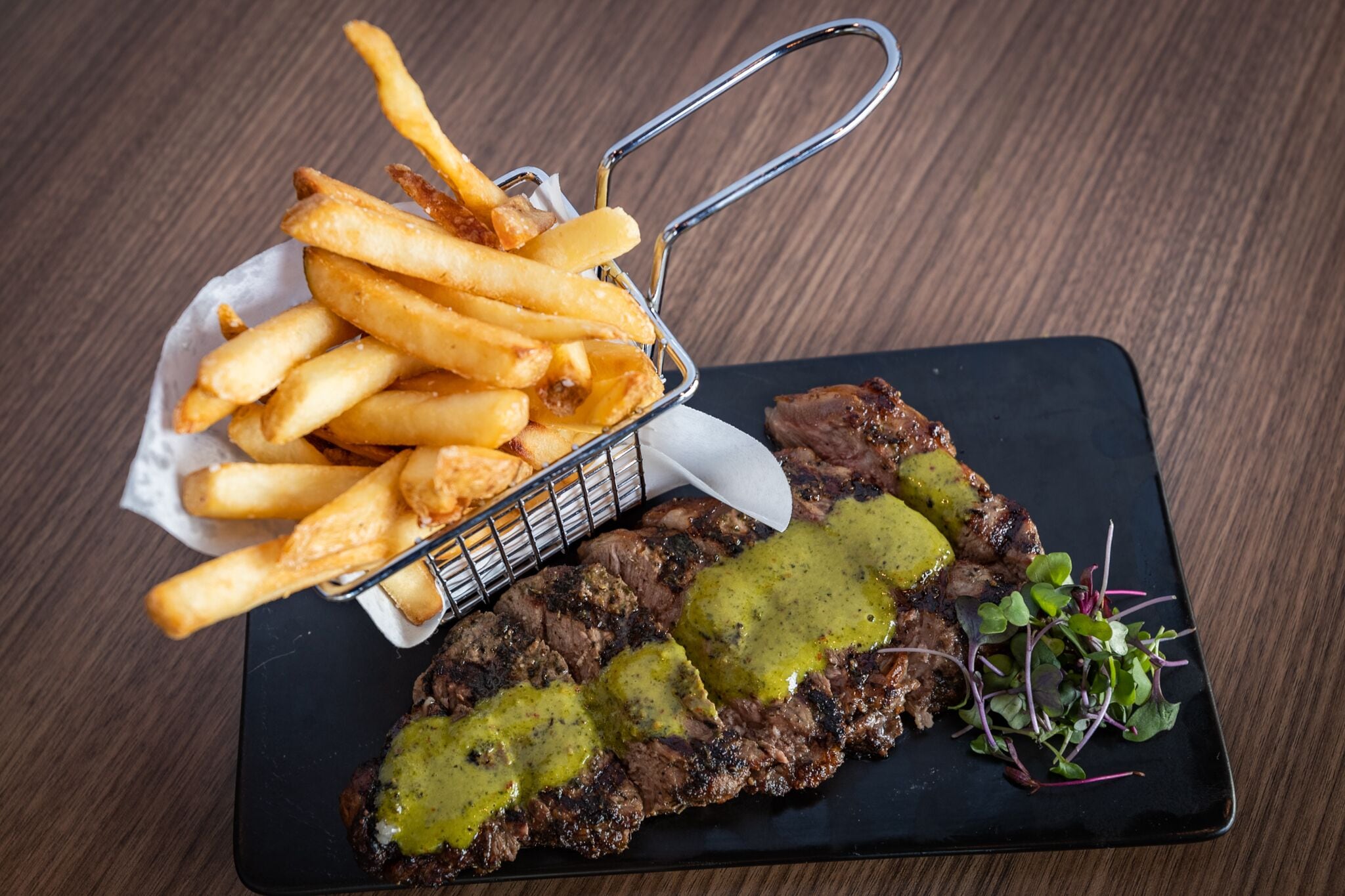 A plate with steak and fries on a wooden table.