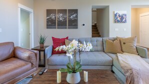 Ein Wohnzimmer mit grauem Sofa, einem braunen Ledersessel und einem Couchtisch mit Kerzen und einer Pflanze.