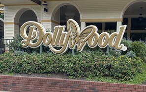 A large sign with the text "Dolly Food" surrounded by greenery and brickwork. - Simple Southern Charm - Close to all Attractions! (Sevierville)