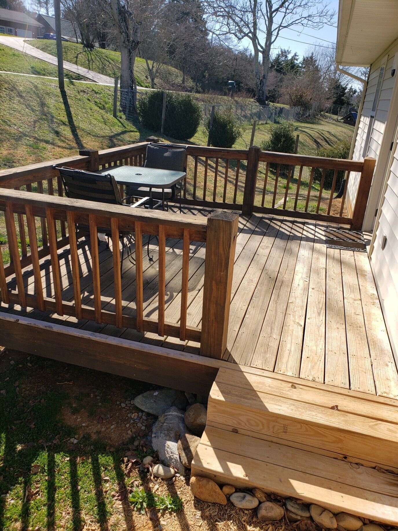 A wooden deck with a table and chairs, surrounded by a wooden railing.