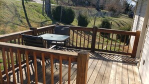 Una terraza de madera con una mesa y sillas, rodeada por un barandal de madera.