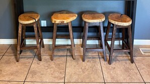 Una zona de bar con mostrador de madera y tres taburetes.