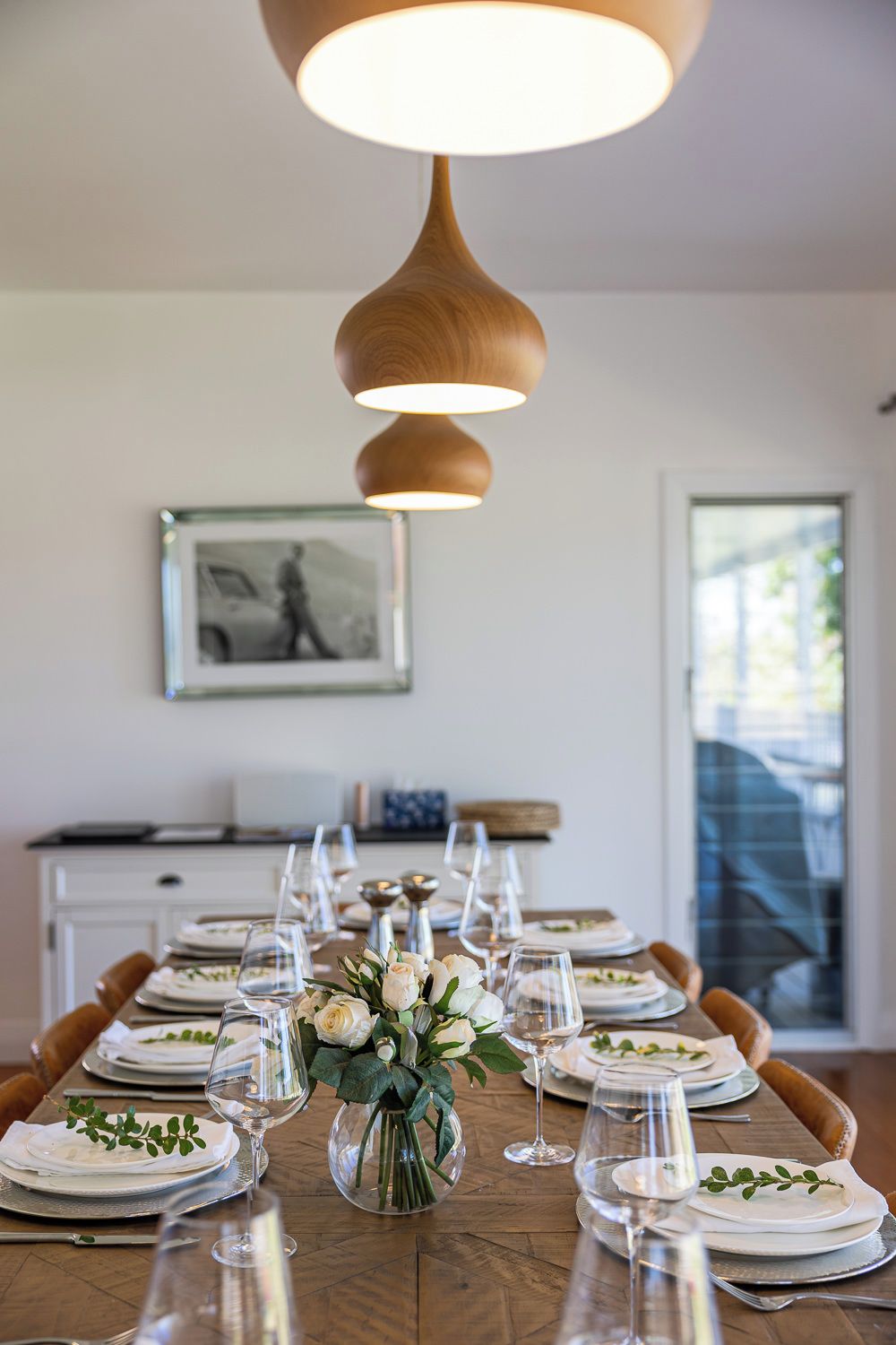 A dining table set with plates, glasses, and a centerpiece of white flowers.