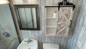 Ein Badezimmer mit einer Holzverkleidung, einem weißen Waschbecken, einer Toilette und einem Spiegel.