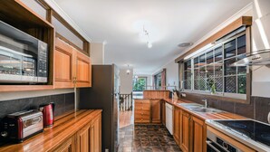 A modern kitchen with wooden cabinets, a stainless steel refrigerator, a microwave, and a stove.