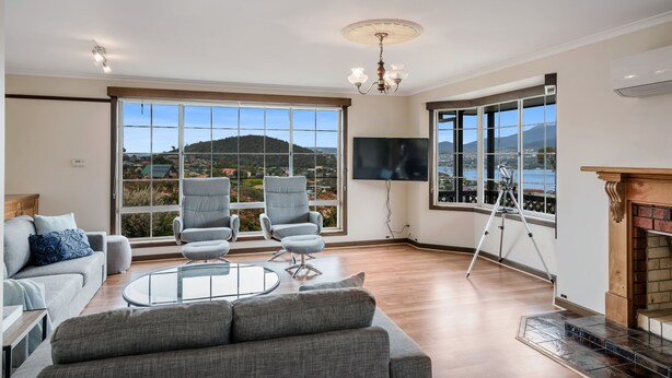 A spacious living room with a large window offering a scenic view, a fireplace, and a flat-screen TV.