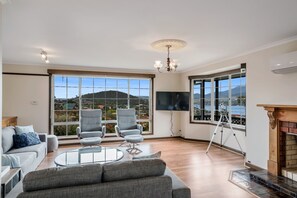 Un salón amplio con un gran ventanal que ofrece vistas panorámicas, una chimenea y un televisor de pantalla plana.