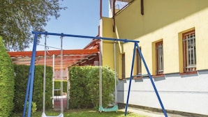 Un quartier résidentiel avec une balançoire dans un jardin, un bâtiment jaune doté de fenêtres et une haie.