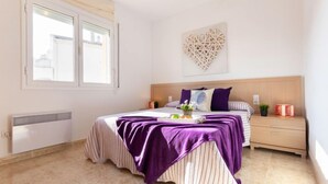 A bedroom with a bed, a nightstand, a decorative wall piece, and a window. - Roquemar by Interhome (L'Ampolla)