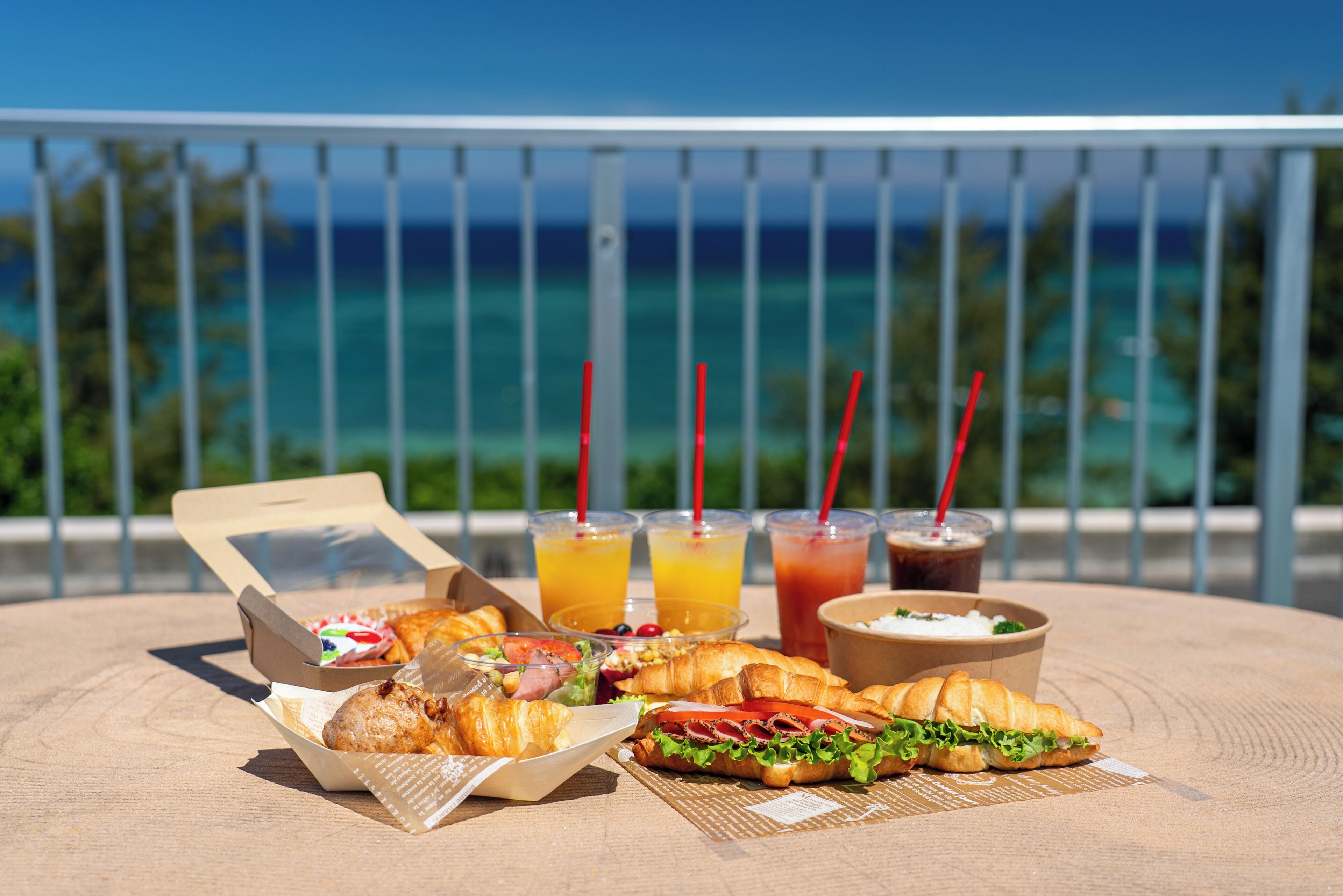 Un tavolo con cibo e bevande su un balcone con vista sull'oceano.