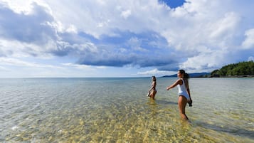 Una vista despejada de una playa con dos personas en el agua.