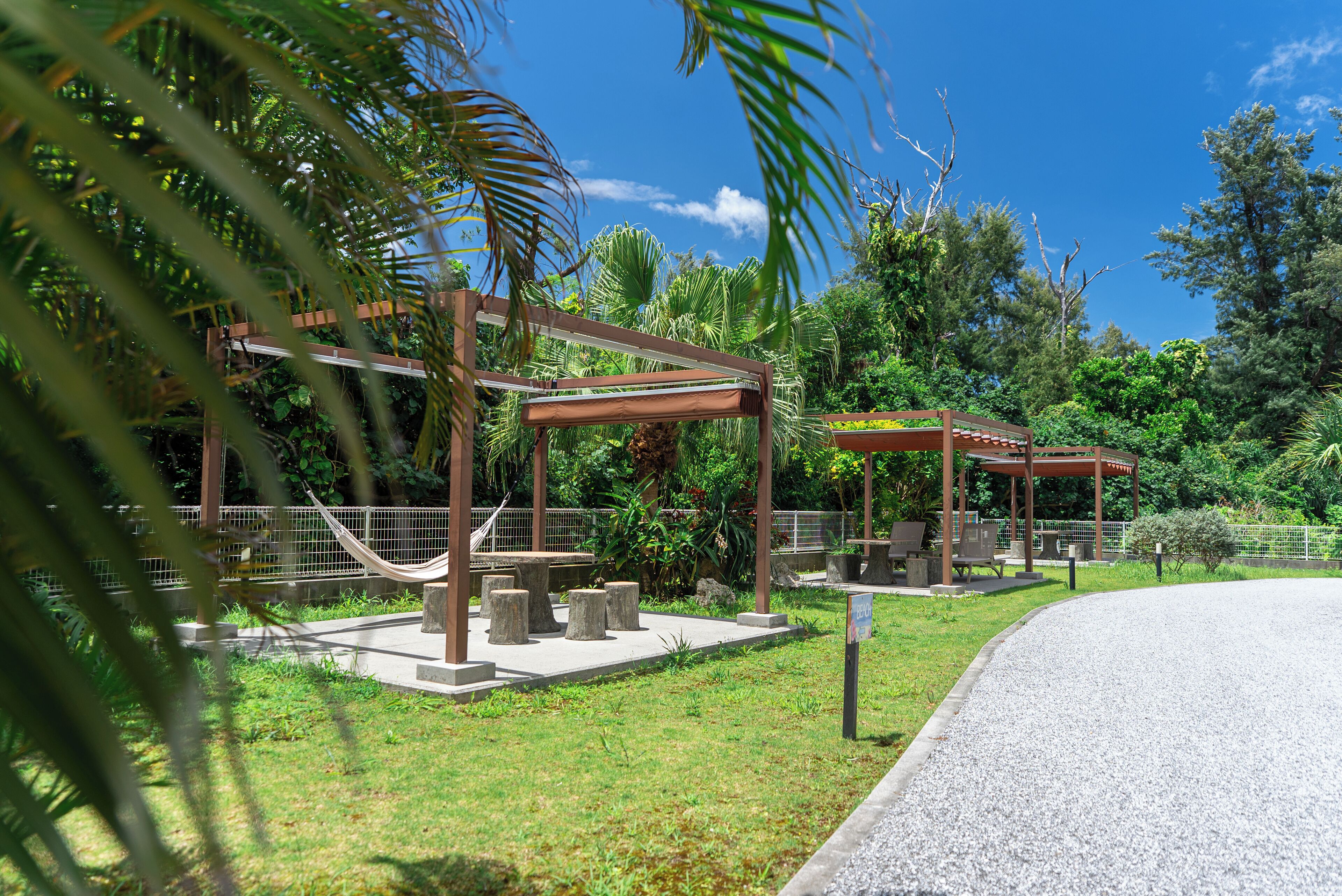 A gazebo with benches and a hammock in a lush garden setting.