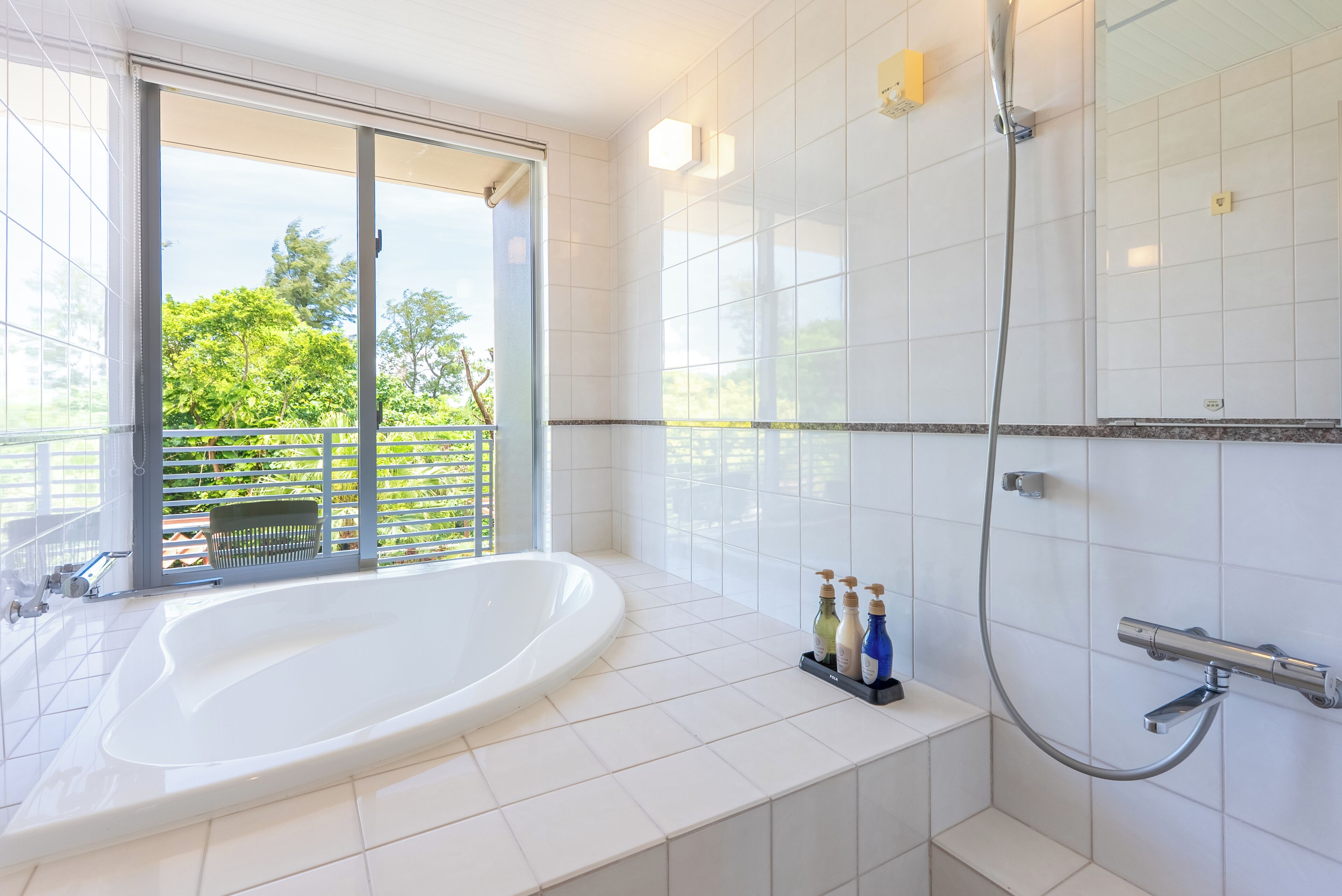 Un baño moderno con una bañera grande, ducha y vistas a través de un ventanal corredero.