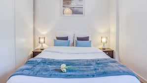 Una camera da letto con un letto, due abat-jour, un quadro appeso al muro e una coperta blu.